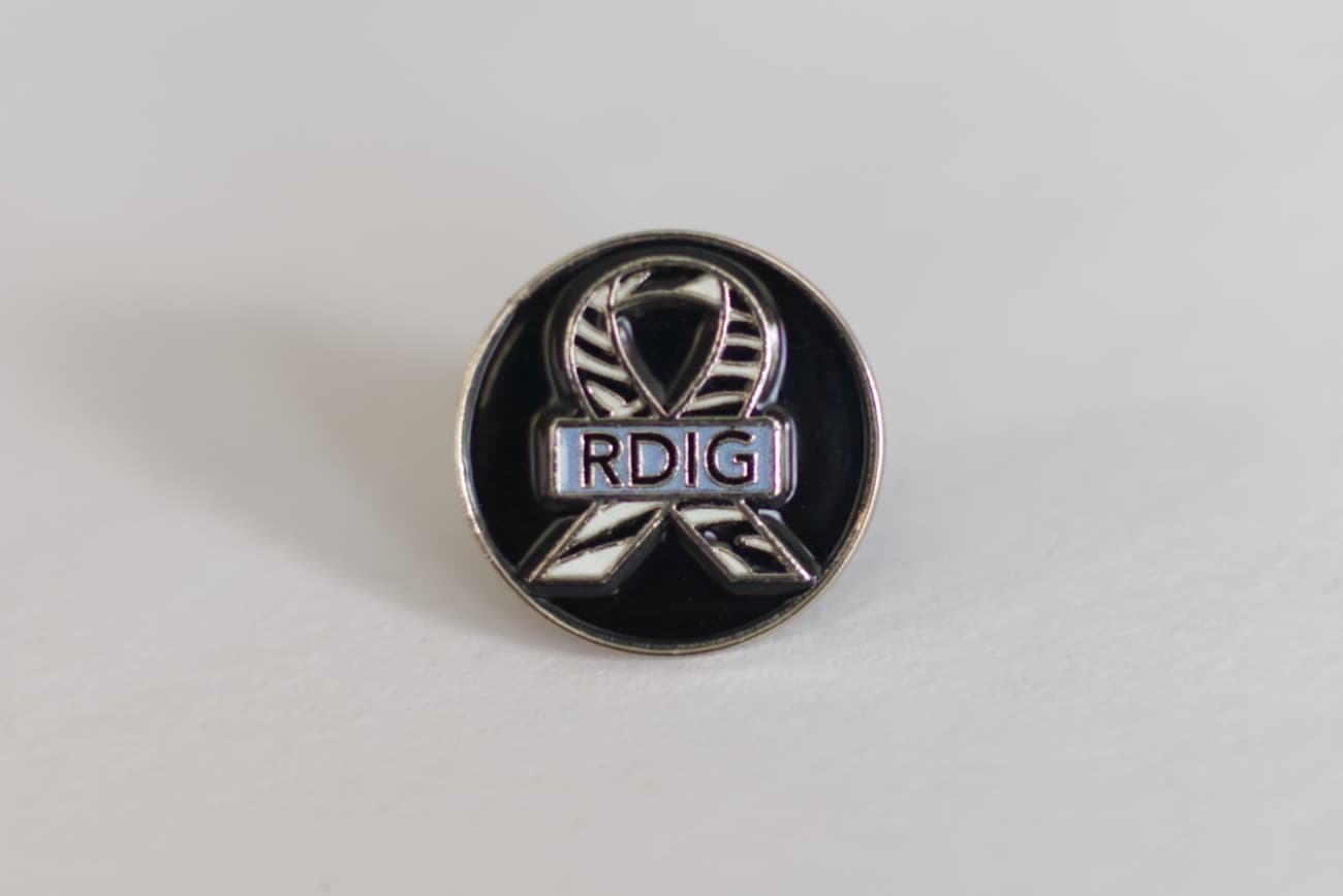 The RDIG soft enamel pin sitting on a white surface